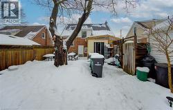 Snow covered house featuring a fenced backyard, brick siding, and an outbuilding - 