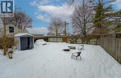 Snowy yard featuring a fenced backyard and a storage unit - 