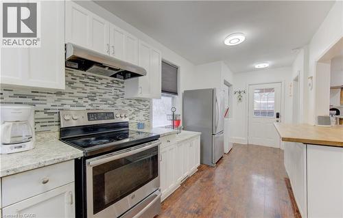 Kitchen featuring stainless steel appliances, white cabinets, under cabinet range hood, and dark wood-style flooring - 569 Stirling Avenue S, Kitchener, ON - Indoor Photo Showing Kitchen