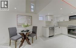 Kitchen featuring stainless steel appliances, light stone countertops, white cabinets, light marble finish flooring, and decorative backsplash - 