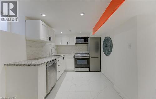 Kitchen featuring white cabinets, appliances with stainless steel finishes, light stone countertops, decorative backsplash, and light marble finish flooring - 569 Stirling Avenue S, Kitchener, ON - Indoor Photo Showing Kitchen
