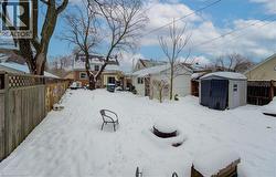 Yard layered in snow featuring a fenced backyard and a shed - 