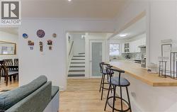 Kitchen with a breakfast bar area, white cabinetry, glass insert cabinets, light wood finished floors, and butcher block counters - 
