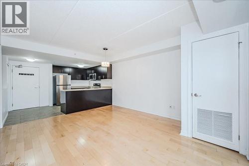 Kitchen with a peninsula, light countertops, open floor plan, appliances with stainless steel finishes, and light wood finished floors - 41 Goodwin Drive Unit# 202, Guelph, ON - Indoor Photo Showing Kitchen