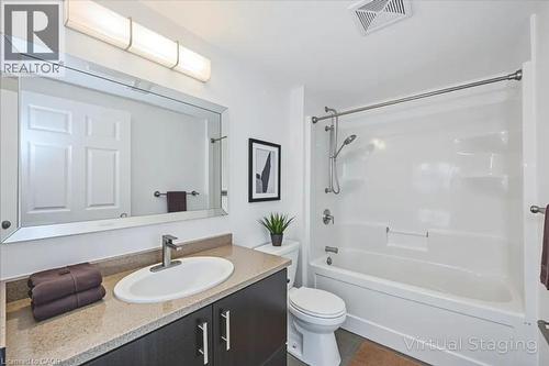 Bathroom featuring bathing tub / shower combination, vanity, and dark tile patterned floors - 41 Goodwin Drive Unit# 202, Guelph, ON - Indoor Photo Showing Bathroom