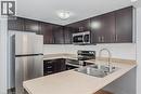 Kitchen with appliances with stainless steel finishes, light countertops, dark brown cabinets, and a peninsula - 41 Goodwin Drive Unit# 202, Guelph, ON  - Indoor Photo Showing Kitchen With Double Sink With Upgraded Kitchen 