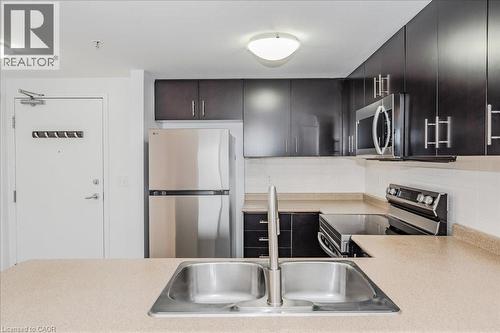 Kitchen featuring appliances with stainless steel finishes, light countertops, and backsplash - 41 Goodwin Drive Unit# 202, Guelph, ON - Indoor Photo Showing Kitchen With Double Sink