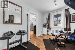 Exercise room with light wood-style flooring, track lighting, and radiator - 