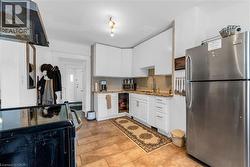 Kitchen with appliances with stainless steel finishes, ventilation hood, white cabinets, and dark stone counters - 