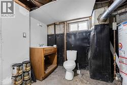 Bathroom featuring vanity, unfinished concrete flooring, and water heater - 