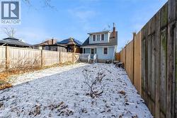 Snow covered house featuring a fenced backyard, a wooden deck, and a chimney - 