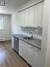 Kitchen with tasteful backsplash, baseboard heating, dishwasher, light wood-type flooring, and white cabinets - 145 Macgregor Crescent Unit# 1, Waterloo, ON  - Indoor Photo Showing Kitchen 