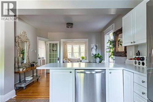 Kitchen featuring white cabinets, a peninsula, stainless steel appliances, light wood finished floors, and light countertops - 58 Chatham Street, Hamilton, ON - Indoor Photo Showing Kitchen