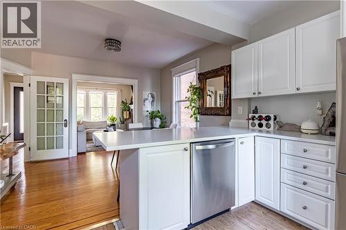 Kitchen with white cabinets, a peninsula, dishwasher, and light wood-type flooring - 58 Chatham Street, Hamilton, ON - Indoor Photo Showing Kitchen