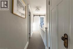 Hallway featuring carpet, a barn door, and an upstairs landing - 