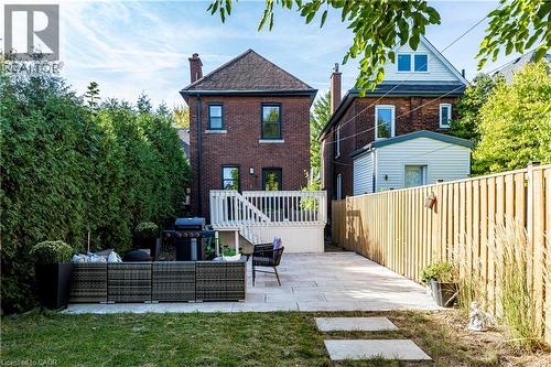 Back of property featuring a patio, an outdoor hangout area, brick siding, and a chimney - 58 Chatham Street, Hamilton, ON - Outdoor With Deck Patio Veranda