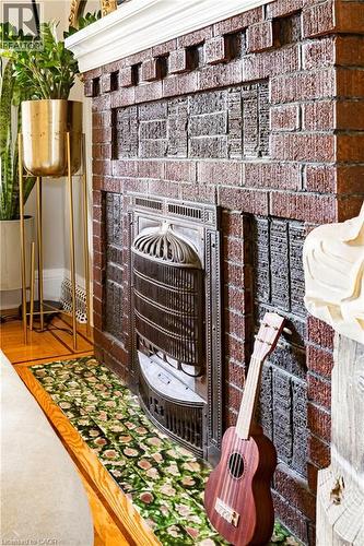 Detailed view of a brick fireplace and wood finished floors - 58 Chatham Street, Hamilton, ON - 