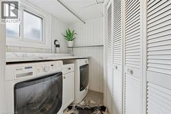 Laundry area featuring wooden walls and washer and clothes dryer - 