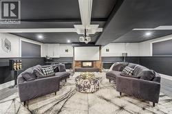 Cinema featuring a fireplace with raised hearth, a decorative wall, and wood finished floors - 