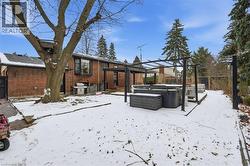 Snow covered house featuring a hot tub, brick siding, a deck, and a pergola - 