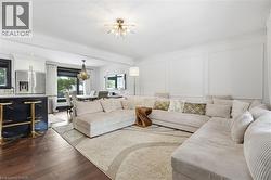 Living area with a chandelier, dark wood-type flooring, and a decorative wall - 