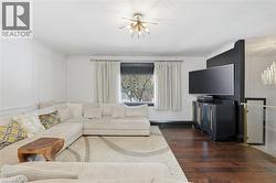 Living area featuring a chandelier and dark wood-style flooring - 