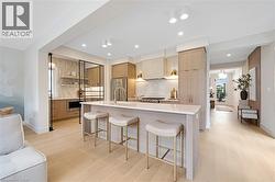 Kitchen with open shelves, a breakfast bar, light countertops, light wood-type flooring, and recessed lighting - 