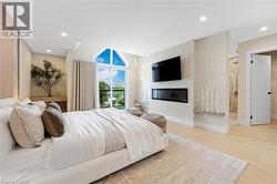 Bedroom featuring light wood-style floors, recessed lighting, access to outside, and a glass covered fireplace - 