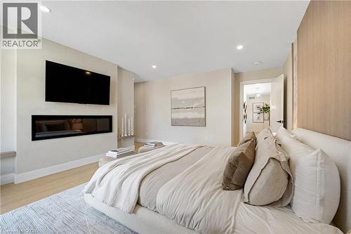 Bedroom with a glass covered fireplace, wood finished floors, and recessed lighting - 452 Westhaven Street, Waterloo, ON - Indoor Photo Showing Bedroom With Fireplace