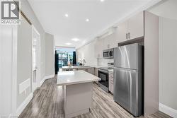 Kitchen featuring a breakfast bar area, appliances with stainless steel finishes, a kitchen island, light laminate flooring, and recessed lighting - 