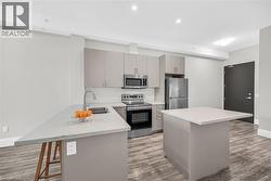 Kitchen featuring a breakfast bar area, appliances with stainless steel finishes, a kitchen island, light laminate flooring, and recessed lighting - 