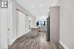 Kitchen featuring light countertops, gray cabinetry, a kitchen island, recessed lighting, and freestanding refrigerator - 