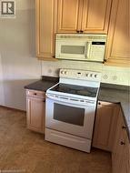 Kitchen featuring white appliances, dark countertops, and decorative backsplash - 