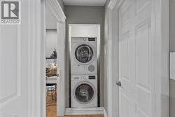 Laundry area with stacked washing machine and dryer and light wood-type flooring - 