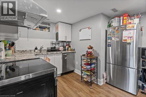 Kitchen featuring ventilation hood, appliances with stainless steel finishes, white cabinets, tasteful backsplash, and light stone countertops - 50 Grove Crescent, Brantford, ON - Indoor Photo Showing Kitchen