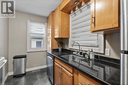 Kitchen featuring dark stone counters, appliances with stainless steel finishes, and brown cabinets - 50 Grove Crescent, Brantford, ON - Indoor Photo Showing Kitchen