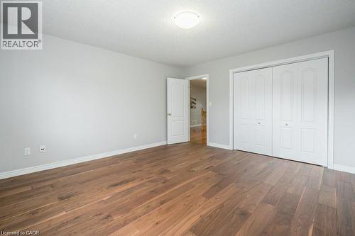 Unfurnished bedroom featuring dark wood-style floors, a closet, and a textured ceiling - 609 Woolgrass Avenue, Waterloo, ON - Indoor Photo Showing Other Room