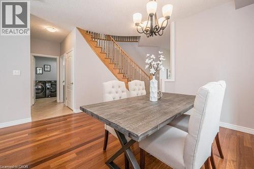 Dining area with a chandelier, washing machine and clothes dryer, light wood-style floors, and stairway - 609 Woolgrass Avenue, Waterloo, ON - Indoor Photo Showing Dining Room