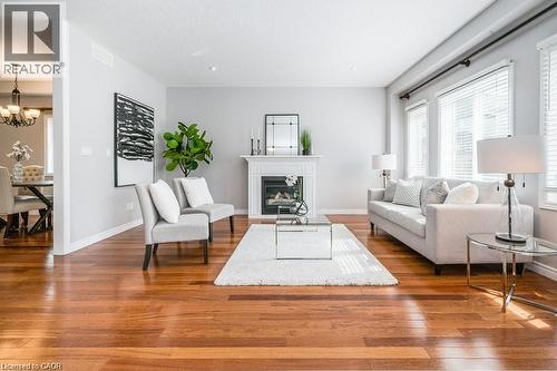 Living area with a glass covered fireplace, hardwood / wood-style flooring, and a chandelier - 609 Woolgrass Avenue, Waterloo, ON - Indoor Photo Showing Living Room With Fireplace