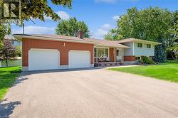 Split level home with asphalt driveway, an attached garage, brick siding, and covered porch - 