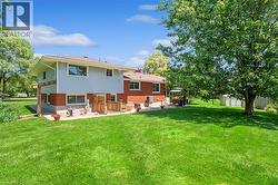Back of property featuring brick siding, a lawn, a patio area, a chimney, and a storage unit - 