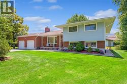 Tri-level home with a garage, a front yard, driveway, and brick siding - 