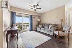 Living room featuring dark wood-type flooring and ceiling fan - 