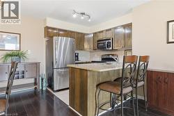 Kitchen featuring stainless steel appliances, a breakfast bar, a peninsula, decorative backsplash, and light stone countertops - 