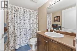 Full bathroom featuring vanity, curtained shower, and light tile patterned floors - 