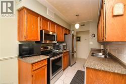 Kitchen featuring stainless steel appliances, backsplash, brown cabinets, and light tile patterned floors - 