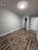 Unfurnished bedroom featuring a textured ceiling, dark wood-style floors, and a closet - 