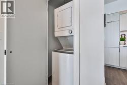 Laundry room featuring stacked washing machine and dryer and dark wood-type flooring - 