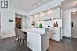 Kitchen with light countertops, a kitchen breakfast bar, dark wood-type flooring, a center island, and modern cabinets - 