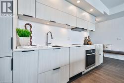 Kitchen with wall oven, dark wood-style flooring, recessed lighting, modern cabinets, and range hood - 